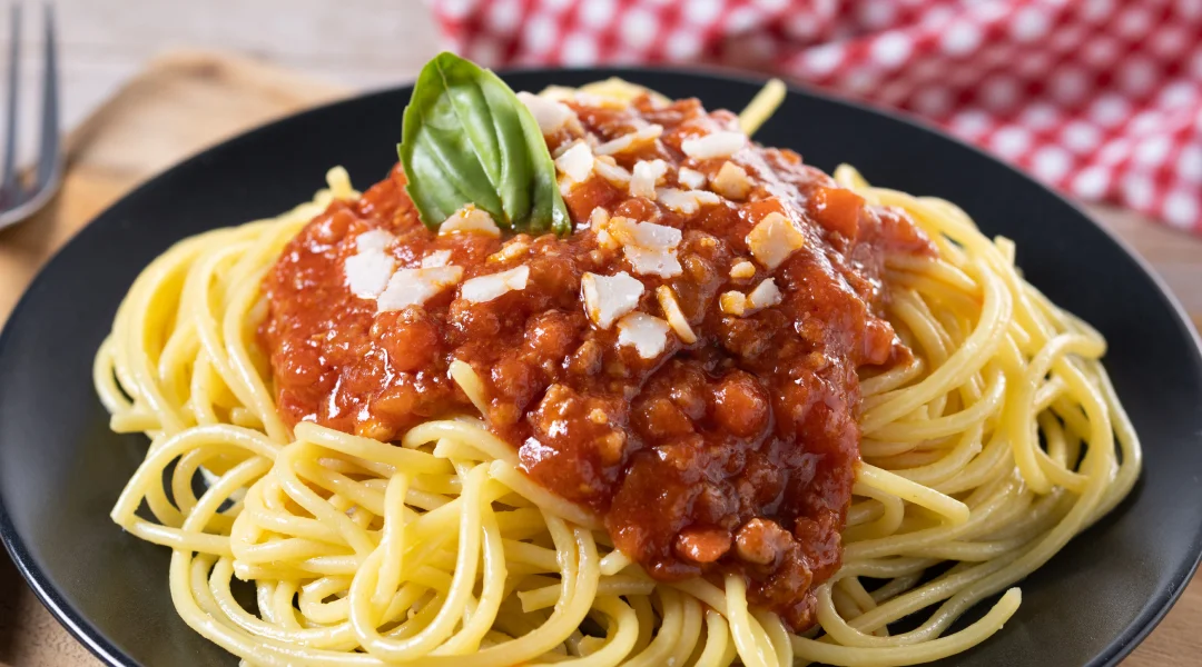 Spaghetti à la sauce tomate et basilic sur une assiette noire.