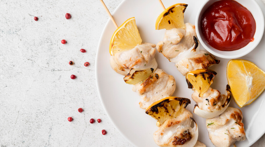 Des brochettes de poulet grillées et colorées, servies avec des légumes frais sur un plateau en bois.