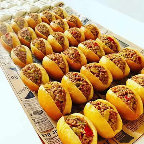 Un plateau de hot-dogs garnis de viande et de légumes, idéal pour un repas de Noël simple et convivial.